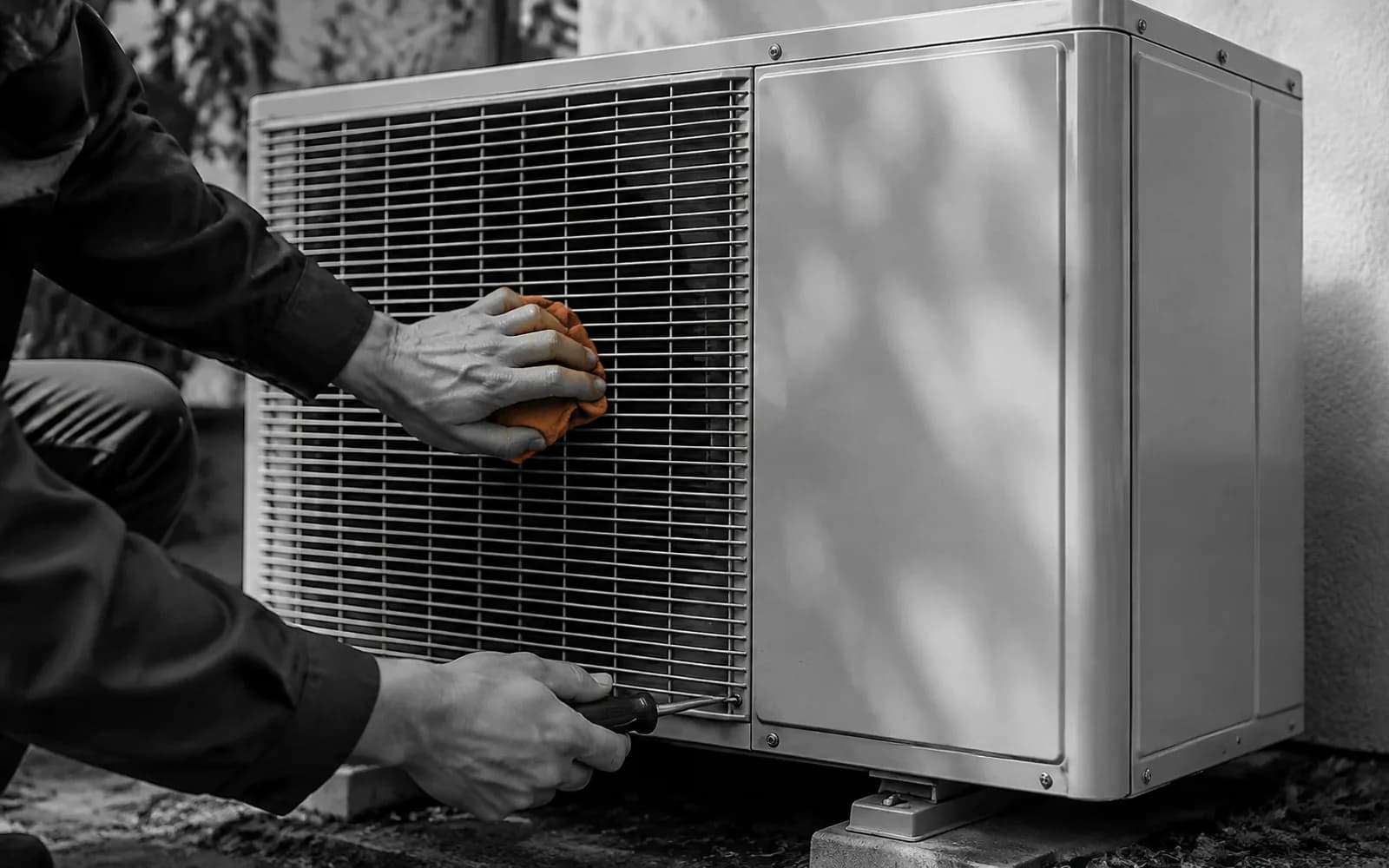 Manos de un técnico revisando una unidad exterior en blanco y negro